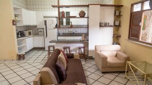 Ein gemütlicher Wohnraum mit einer Küchenzeile, einem Sofa, einem Sessel und einem kleinen Tisch.