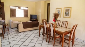 Un salon avec un canapé, un téléviseur et une table à manger avec des chaises.