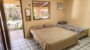 Une chambre avec un lit, une petite table, des chaises, un miroir et un appareil de climatisation.