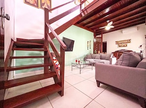 Ein Wohnzimmer mit Treppe, Sofa, Couchtisch und Fernseher.