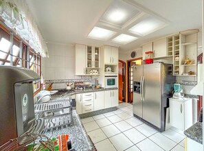 Eine Küche mit weißen Schränken, einem Edelstahl-Kühlschrank, einer Mikrowelle und einem Spülbecken.