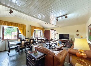 Ein geräumiges Wohnzimmer mit Essbereich, Fernseher und einer Couch.