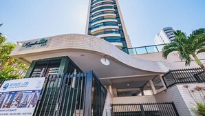 Un edificio moderno con facciata curva, un cartello ben visibile per 'Reformate & CIA', e un alto grattacielo adiacente.
