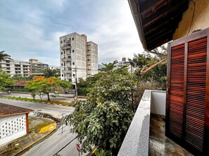 Ein Balkon mit Blick auf eine Stadtlandschaft, darunter ein hohes Gebäude und eine Straße mit Fahrzeugen.
