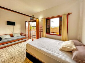 Ein Schlafzimmer mit einem Bett, einer Schlafcouch, einem Fernseher und einem Fenster mit Vorhängen.