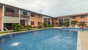 Piscina com fonte de água, rodeada por um edifício com varandas e área de estar ao ar livre.