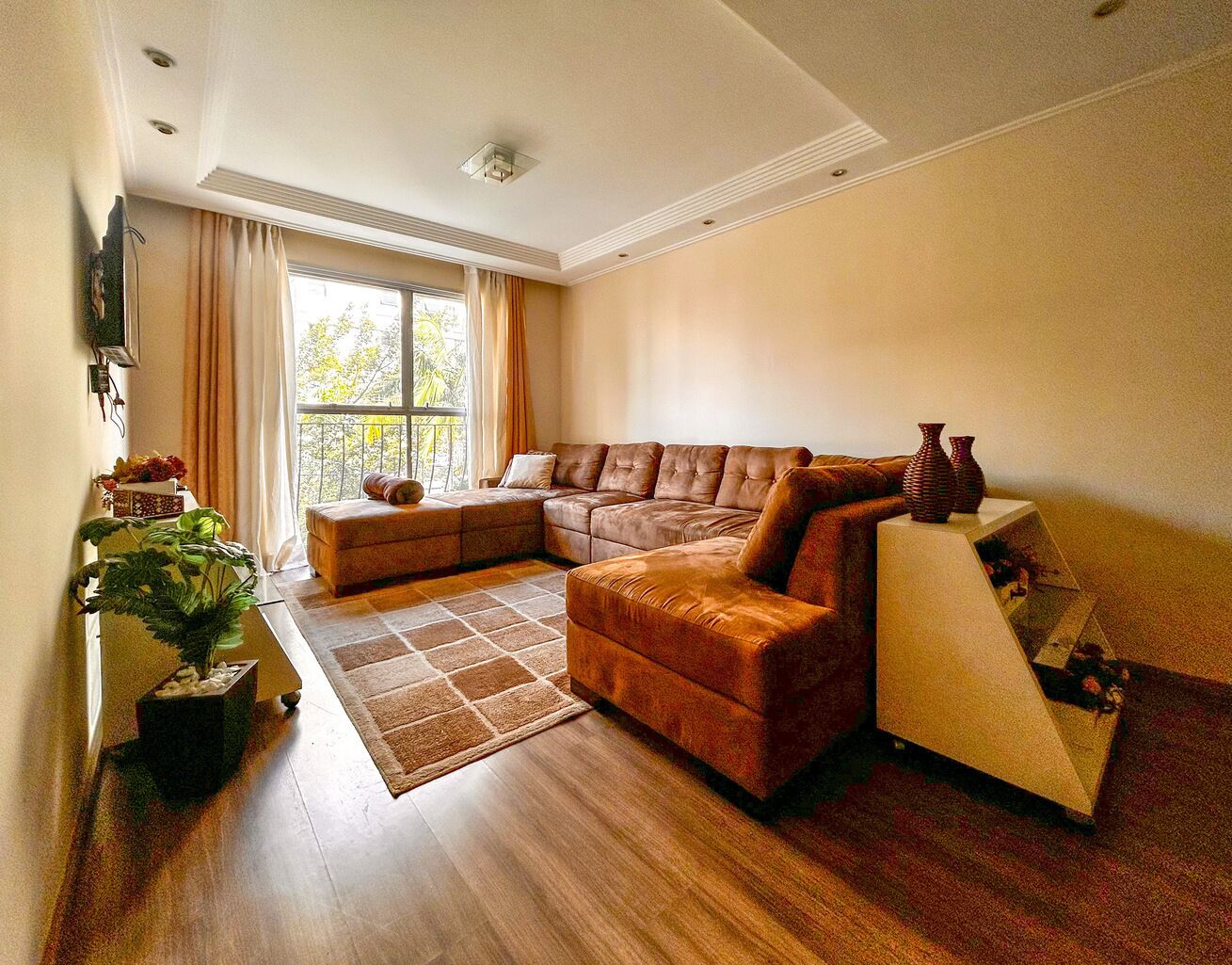 Ein modernes Wohnzimmer mit einem Ecksofa, einem Couchtisch und einer Topfpflanze.