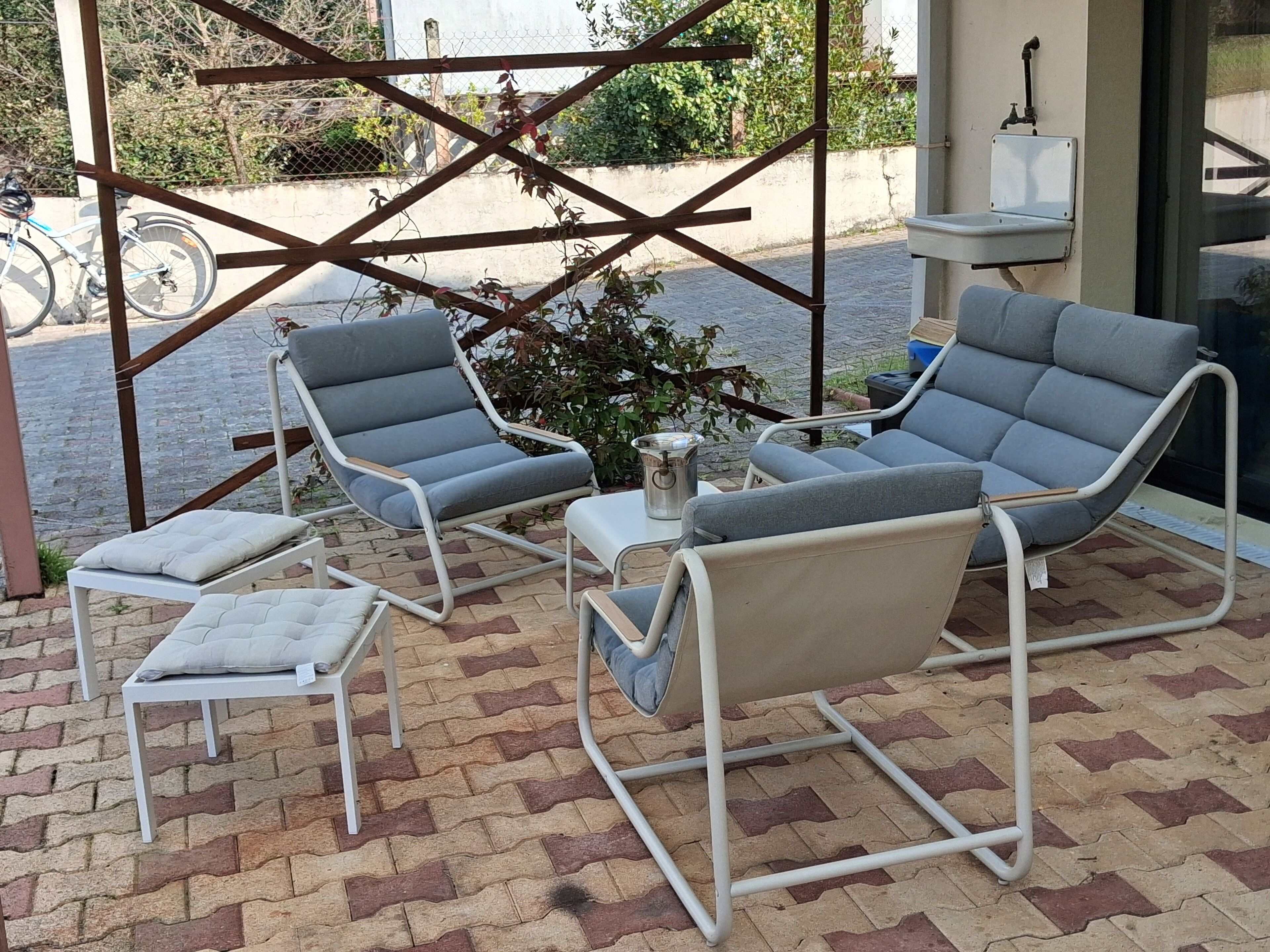 Un patio con dos sillones grises, una mesita y un banco blanco.