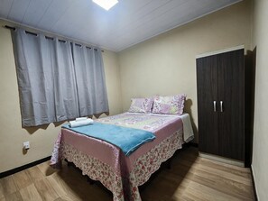 Ein Schlafzimmer mit einem Bett, einem Kleiderschrank und einem Fenster mit Vorhängen.