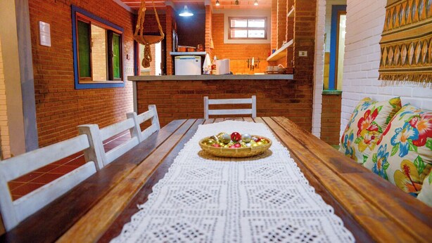 Un comedor acogedor con una mesa de madera, sillas blancas y un camino de mesa de encaje.