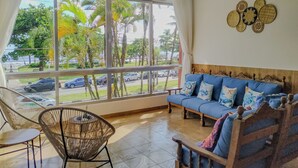 Ein Zimmer mit einem großen Fenster, einem blauen Sofa und einem Korbsessel.