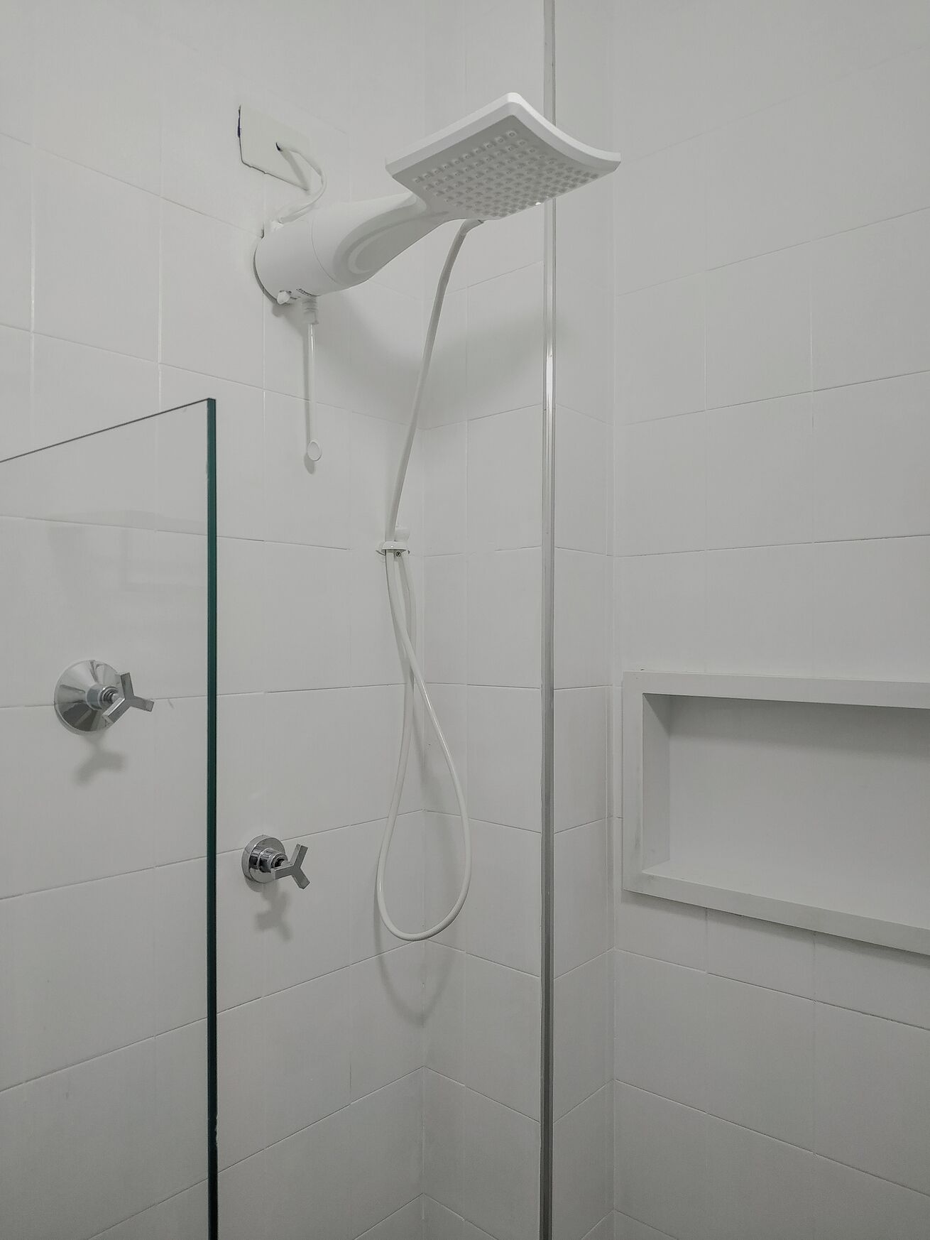 A shower with a handheld showerhead and a wall-mounted control.