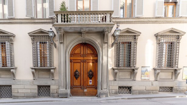 A building facade with a central wooden door, flanked by windows with metal grilles, and a small balcony above. - Bella Benci Frescoed Apartment Central Florence near Uffizi and Ponte Vecchio (Firenze)