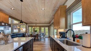 A spacious kitchen with wooden cabinets, a large island, and a view of the outdoors. - Gorgeous 6BD w/ Hot Tub | Mtn VIEWS + Pool Access (Gatlinburg)
