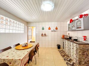 A kitchen with a dining table, chairs, a tiled backsplash, and a window. - Great House with Private Beach in Camaçari/BA (Camacari)