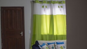 A bedroom with a bed, a blue bean bag, a green and white curtain, and a wooden door. - Paraty Casa equipada a 10 min do centro histórico (Paraty)