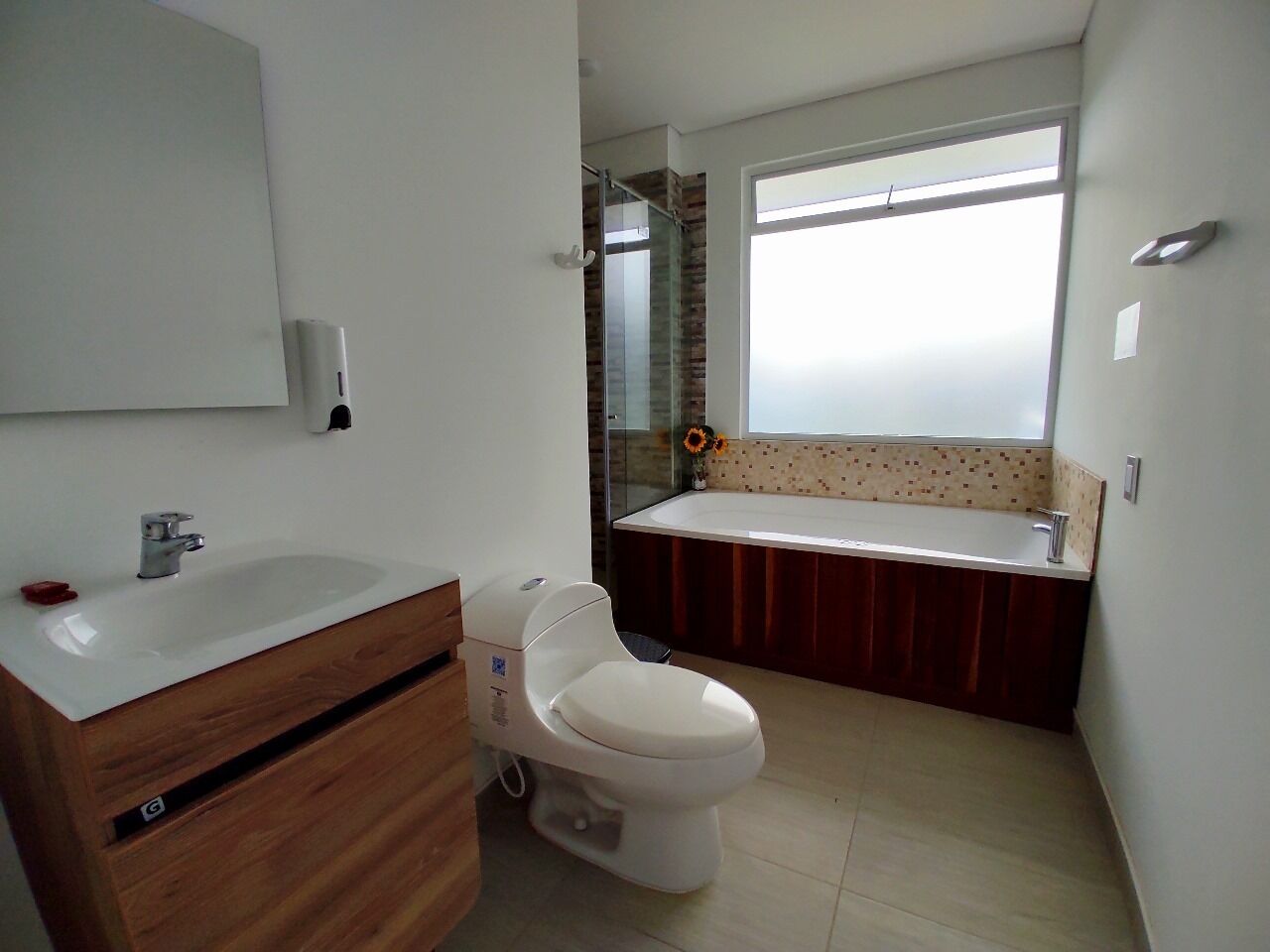 Une salle de bain moderne avec un lavabo, des toilettes et une baignoire, le tout de couleur blanche.