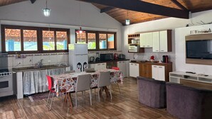 Uma cozinha com área de jantar, vigas de madeira, geladeira, micro-ondas e televisão.