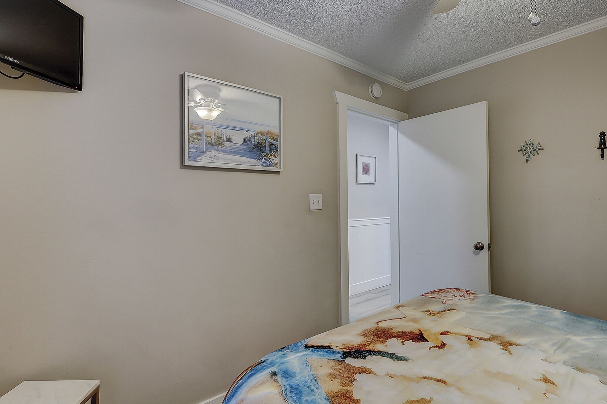 Een slaapkamer met een bed, een schilderij, een deur en een plafondlamp.