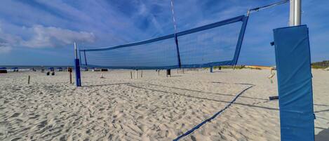 A beach volleyball net set up on a sandy beach with a clear sky.