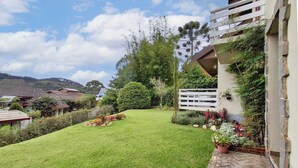 Un giardino curato con prato, diverse piante e un recinto bianco.