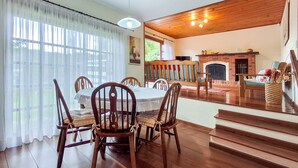 Zona pranzo con tavolo rotondo e sedie in legno, camino e scala che conduce a un piano superiore.
