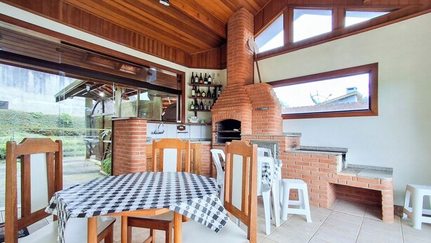Zona pranzo con tovaglia a quadri, sedie in legno e forno a mattoni.
