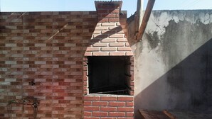 A brick oven structure with a chimney, attached to a brick wall. - Casa com churrasq e Wi-fi prox. de lindas praias (Santa Cruz Cabrália)