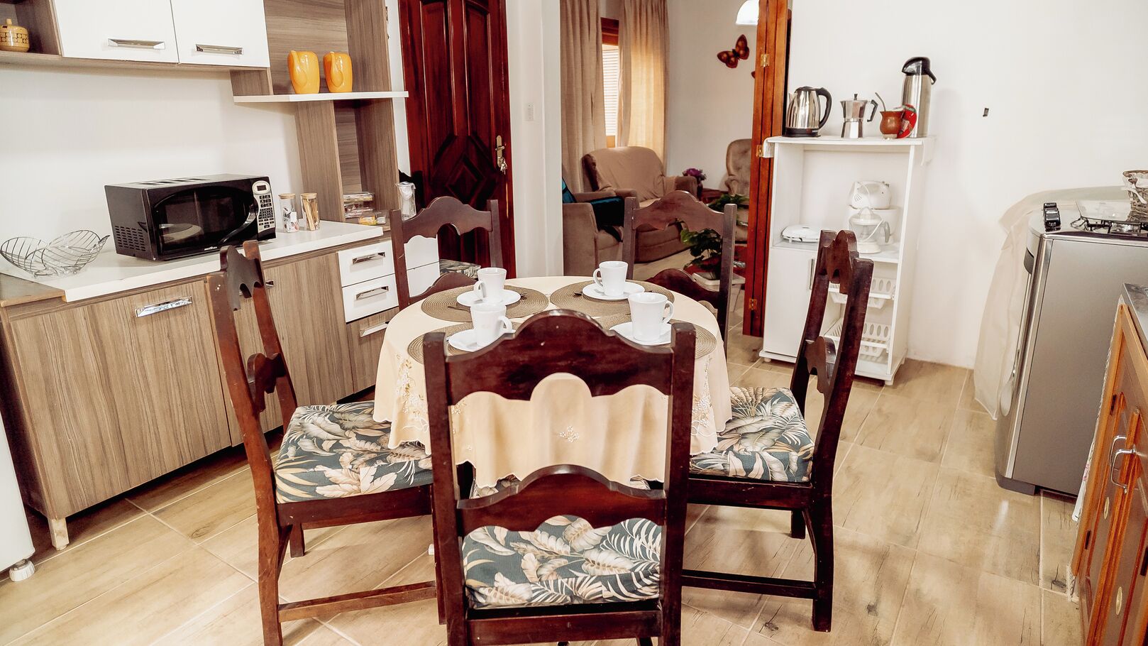 Ein Essbereich mit einem runden Tisch, vier Stühlen, einer Mikrowelle und einem Kühlschrank.