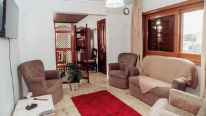 Una sala de estar con dos sofás, un tapete rojo y un panel de madera con diseño de celosía.