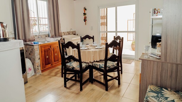 Un comedor con mesa y sillas, una cocina con pileta y placares, y vista por una ventana.