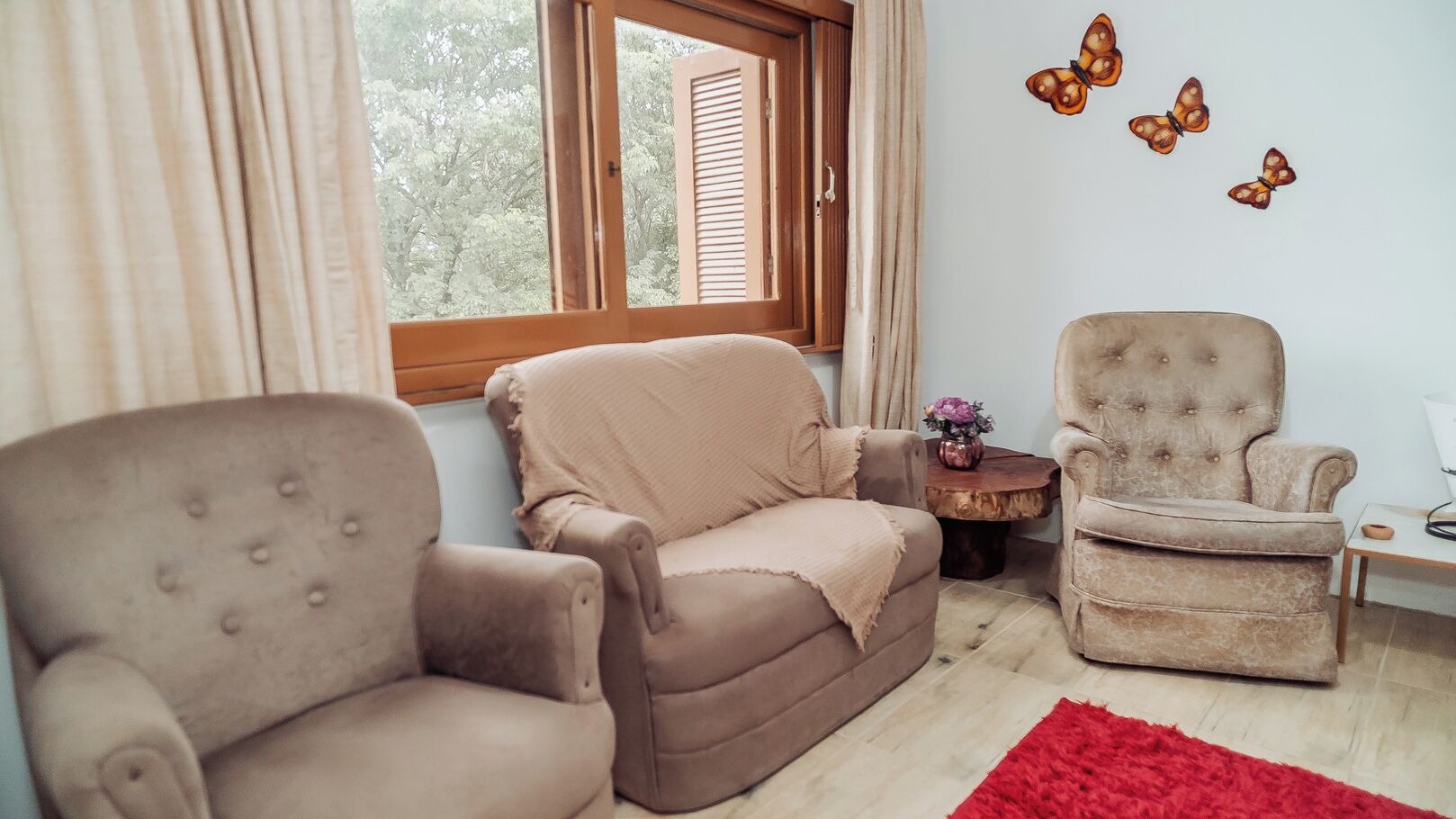 A living room with two armchairs, a small side table with a vase, and a red rug.