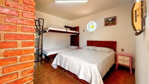 Een kamer met een stapelbed, een enkel bed, een klein nachtkastje, een wandklok en een raam met uitzicht op het platteland.