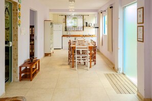 Eine geräumige Küche mit Essbereich, einem Kühlschrank und einem fenster mit Vorhängen.