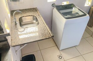 Ein kleiner Waschbereich mit Spüle und einer Waschmaschine mit Frontlader.