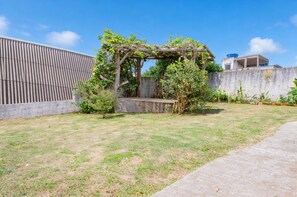 Un jardin agrémenté d’une pergola, d’un mur en béton et d’une pelouse.