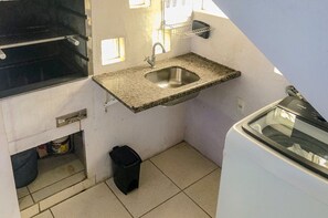 Eine kompakte Küche mit einer Granit-Arbeitsplatte, einem Spülbecken, einer kleinen Mülltonne und einer Waschmaschine.
