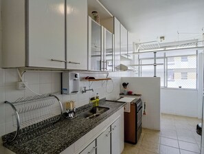Eine Küche mit weißen Schränken, einer Granitarbeitsplatte, einem Edelstahl-Spülbecken und einem Fenster, das für natürliches Licht sorgt.