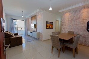 Una sala de estar moderna con comedor, un sofá, un televisor y una pared de ladrillo.