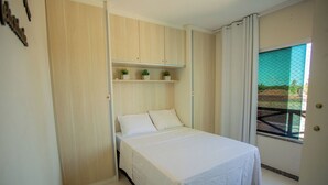 A bedroom with a bed, a wardrobe, and a window with a view.
