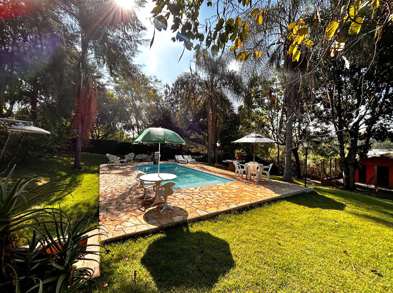 Quintal com piscina, rodeado por um alpendre de pedra, e mobiliado para áreas externas.