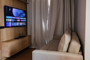 A modern living room with a flat-screen TV mounted on a wooden wall, a beige sofa, and a wooden side table.