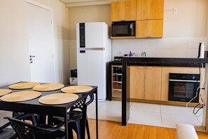 A compact kitchen with a black countertop, a microwave, a built-in oven, and wooden cabinets.