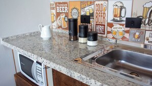 A kitchen counter with a coffee maker, a kettle, and a sink.