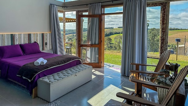 A bedroom with a large bed, a seating area with a view, and a sliding glass door leading to an outdoor area.