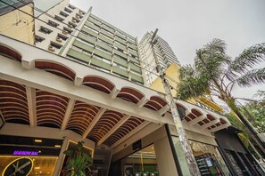 Ein mehrstöckiges Hotel mit modernem Design, gekennzeichnet durch eine markante Überhangkonstruktion und einen sichtbaren Eingangsbereich mit einer Uhr.