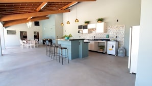 Un'ampia cucina con isola centrale, sgabelli da bar, frigorifero e zona pranzo con sedie.