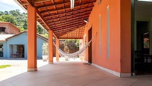 Un'area esterna riparata con un'amaca, un pavimento piastrellato e un edificio con pareti arancioni e un soffitto in legno.