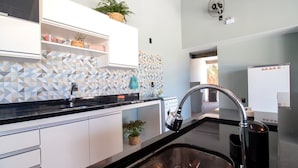 Una cucina moderna con mobili bianchi, un piano di lavoro nero e un backsplash geometrico.