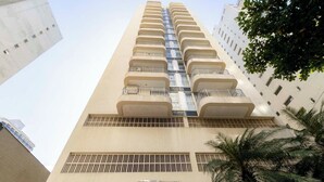 Een hoog gebouw met meerdere balkons, een bordje waarop 'EDIFICIO CABO SAN ROQUE 1500' staat, en een palmboom op de voorgrond.